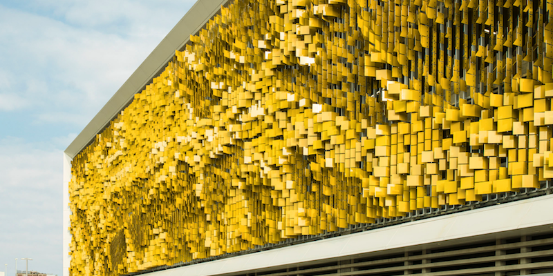 A yellowstainless steel wall with pieces coming from the edge like leaves.