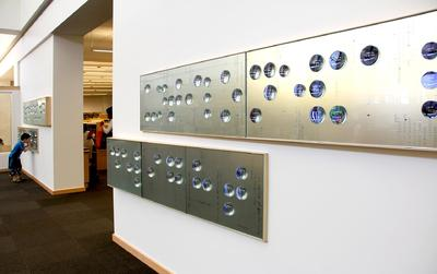 Silver slab on the wall with blue colored balls on top representing braille.