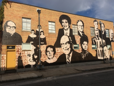 Various celebrities are painted on a brick wall