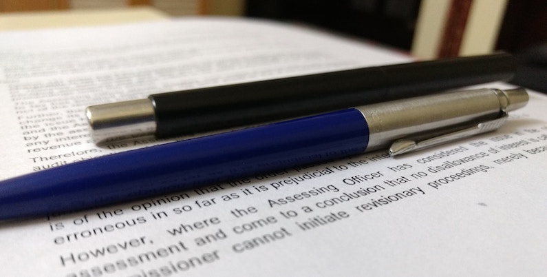 Pens lay on top of a typed paper