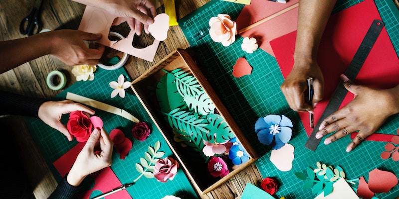 from above looking down on a table with paper cut outs, scissors, paper cutters.