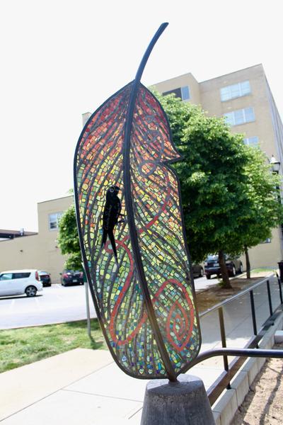 mage of a public art sculpture of a large feather, colored with stained glass.