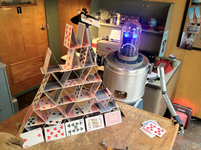 Image of a robot standing next to a house of cards.