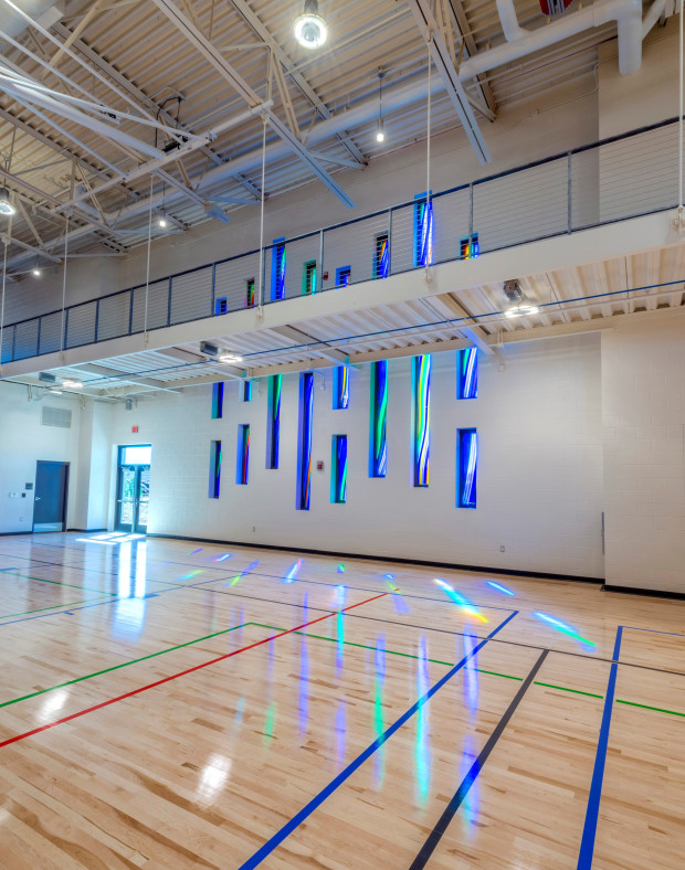 Blue glass sculpture hanging down wall in central rec center in Aurora