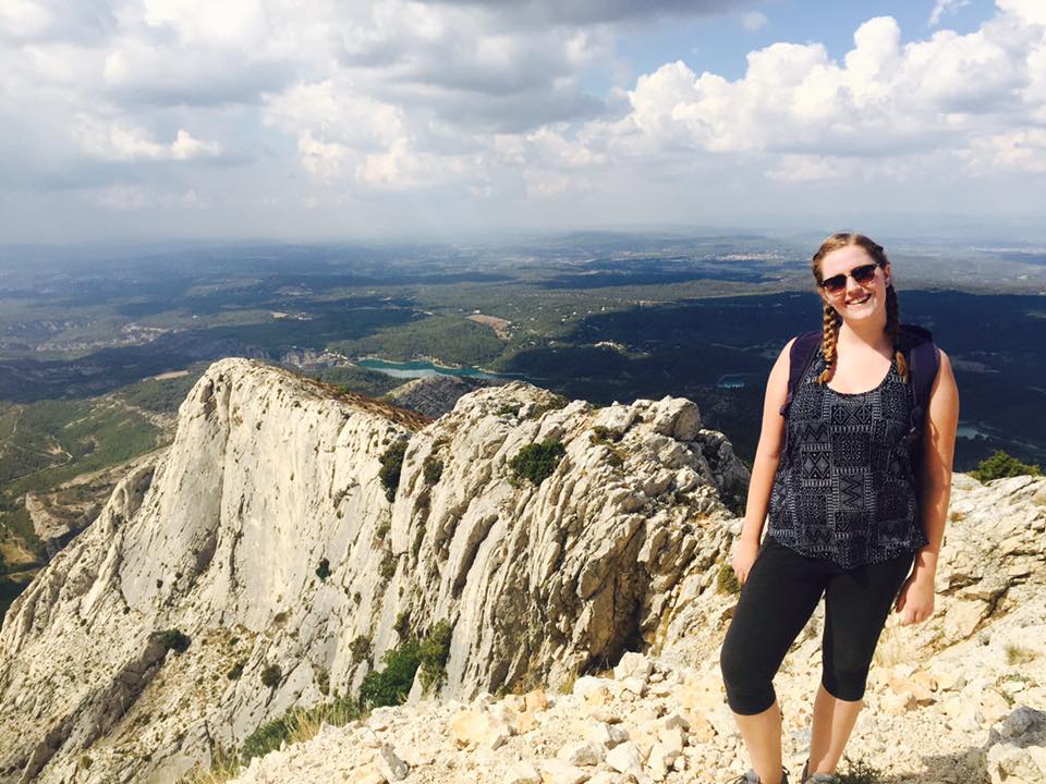 Justine standing in front of a mountain area in France where Paul Cezanne painted Mont Sainte Victoire