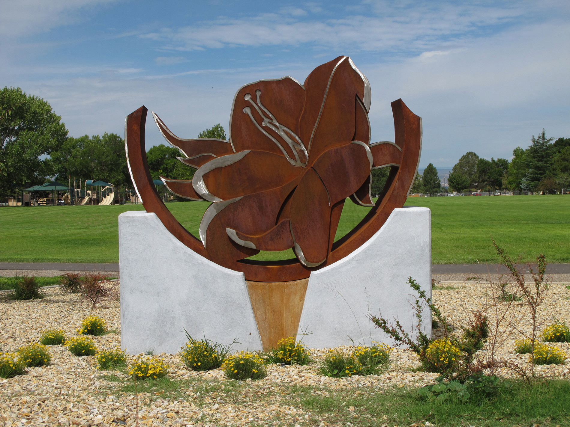 Desert Primrose by Karen Yank bronze flower on top of white stand in the middle of a field