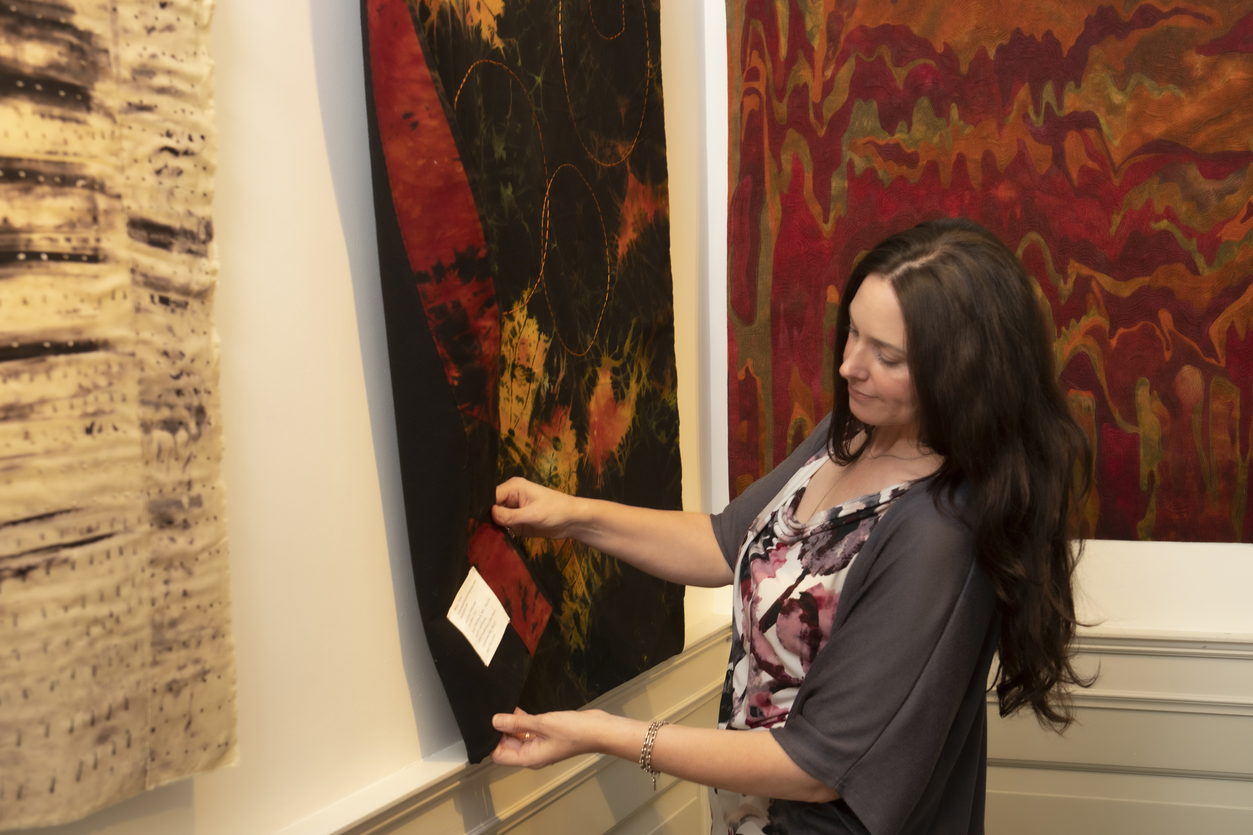 An image of Amy hanging artwork in the gallery.