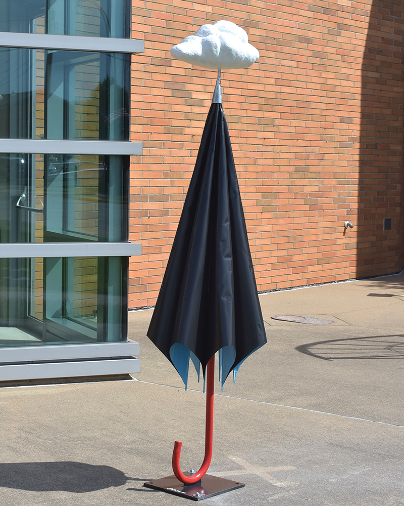 An umbrella standing up on the sidewalk with a cloud above it.