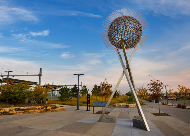 A sculpture near a lot in a cirlce format with poles coming from the sphere.