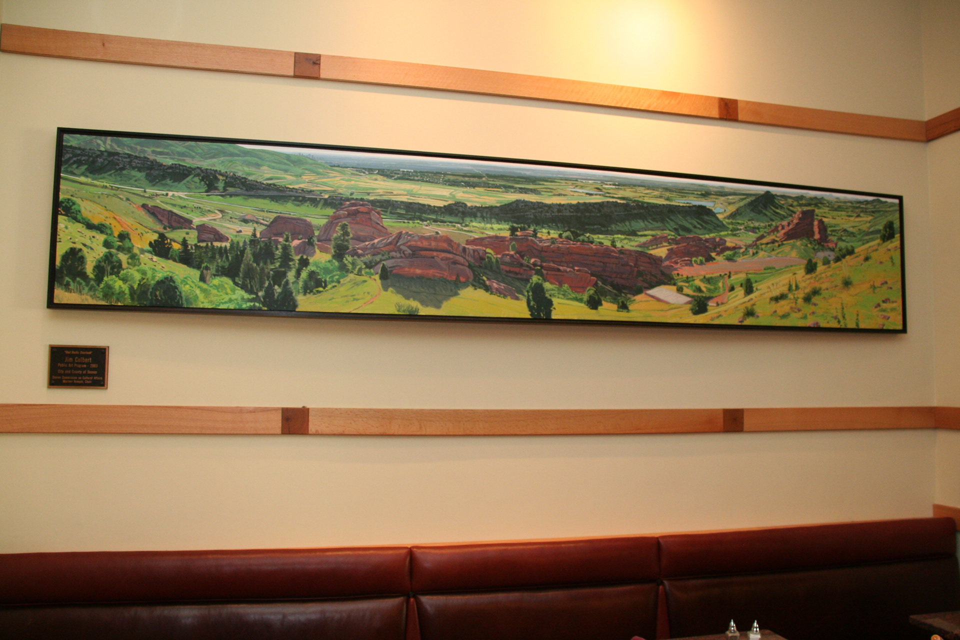 photograph of a wide landscape painting of red rocks park displayed on a wall