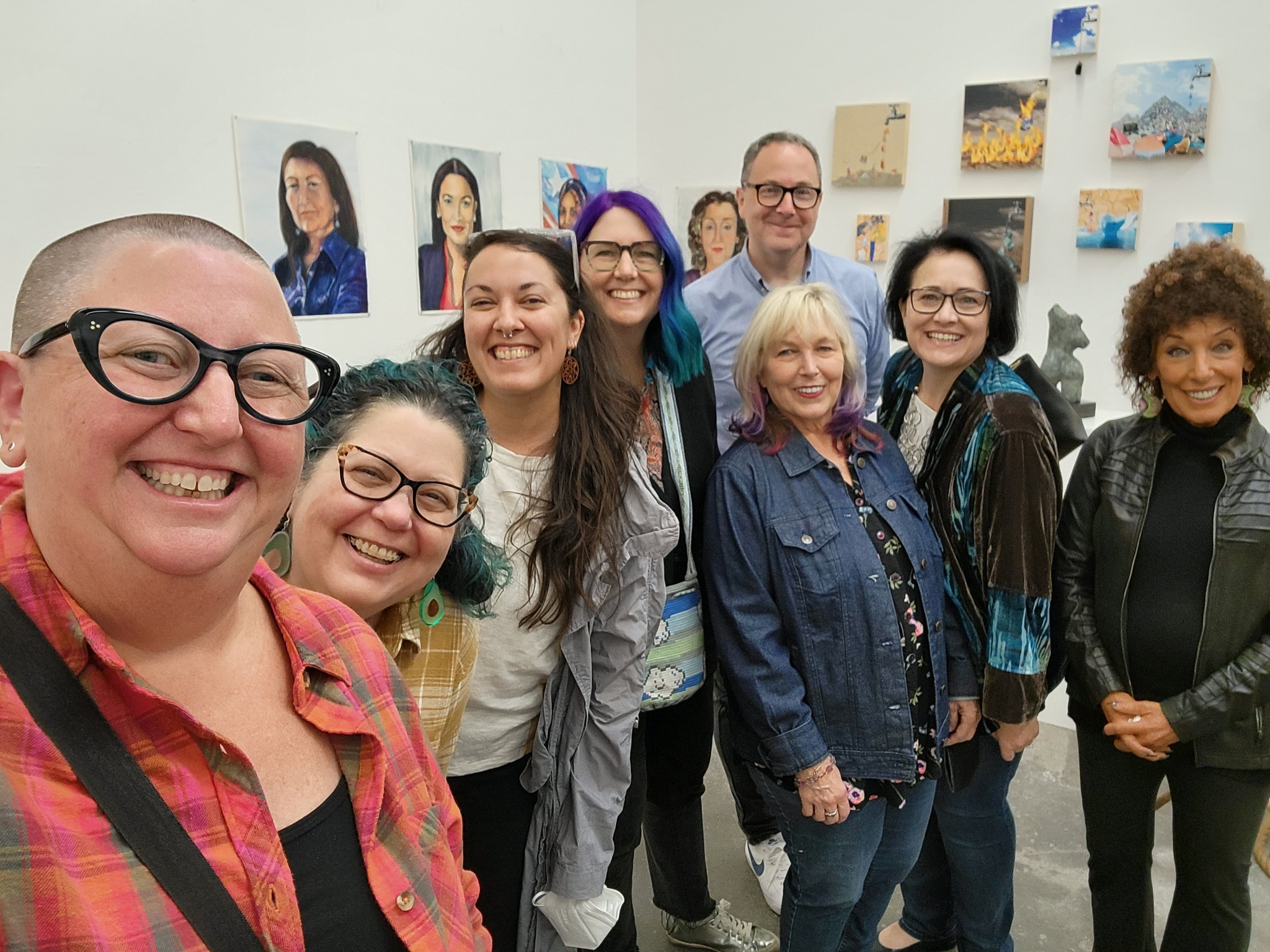 Eight people smiling at the camera, gathered at an art gallery