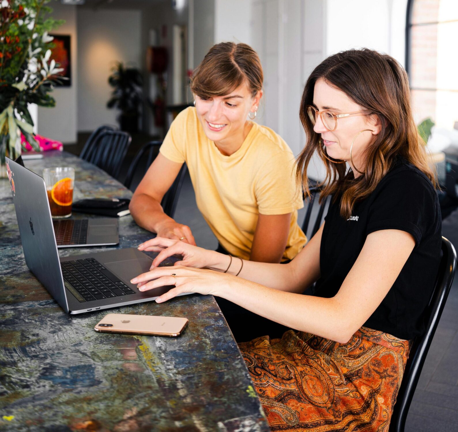 Image of two women sitting next to each other and looking at a laptop