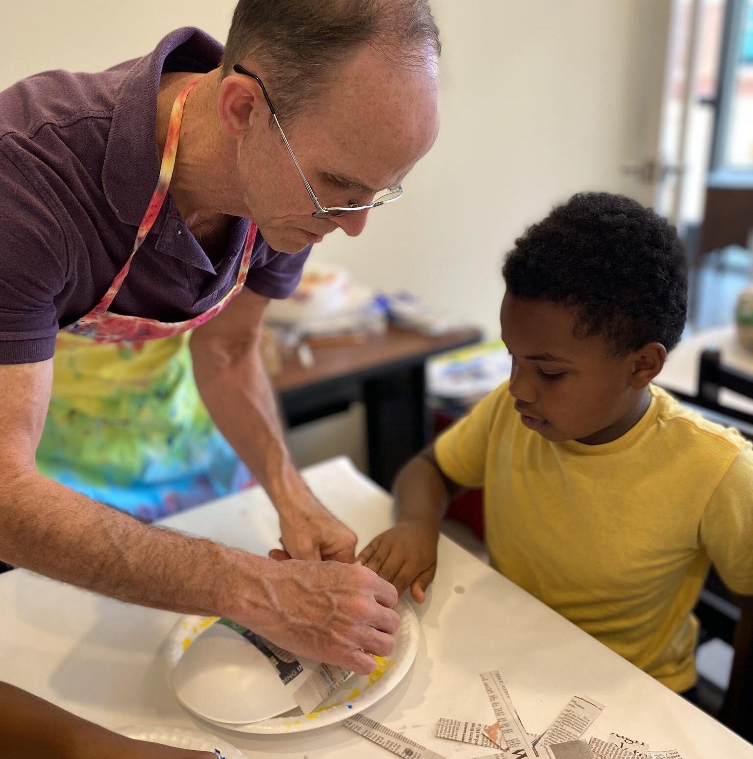 Lanier Williams, one of d'Art Center's children's camp instructors, helping a child with an art piece.