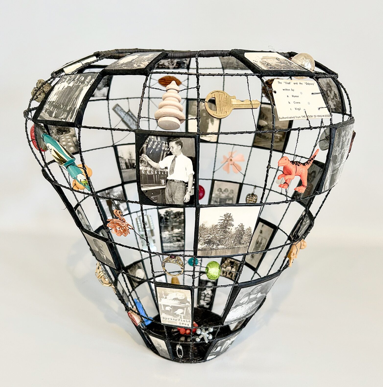 Balloon-shaped wireframe sculpture with photos and miniatures in a grid.