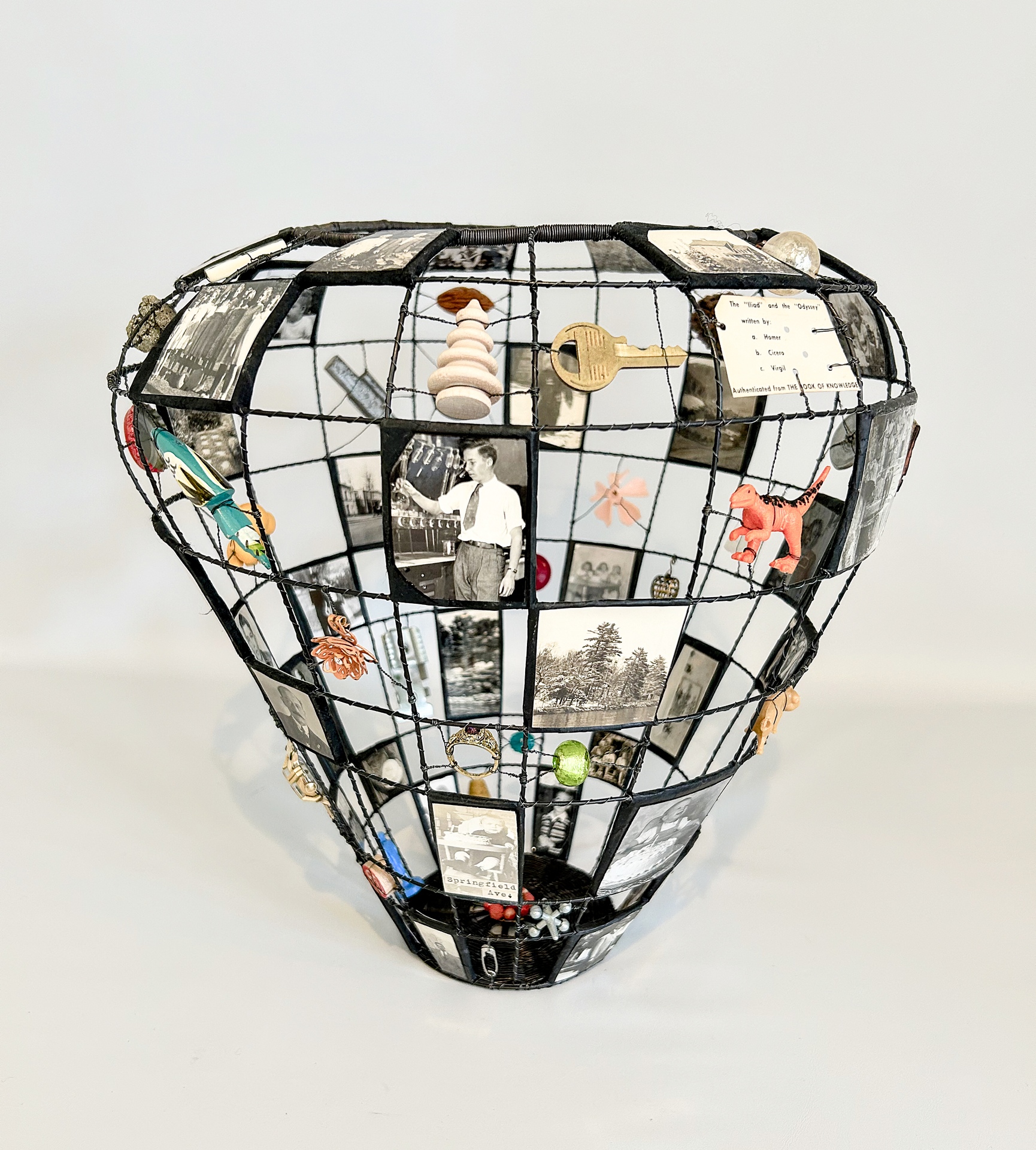 Balloon-shaped wireframe sculpture with photos and miniatures in a grid.